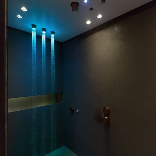 Eine Dusche mit blauem Licht in einer Badausstellung. | casaceramica