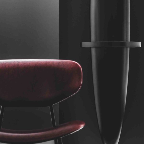 Ein Schwarz-Weiß-Foto eines Stuhls vor einer dunklen Wand. | casaceramica