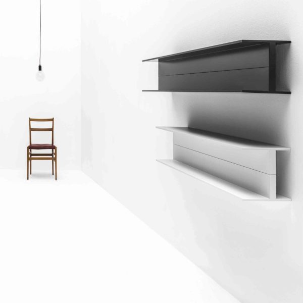 Ein weißer Raum mit einem schwarzen Regal und einem Stuhl zur Badausstellung. | casaceramica