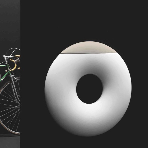 Ein Fahrrad lehnt an einer Wand neben einem weißen Donut in einer Badausstellung. | casaceramica