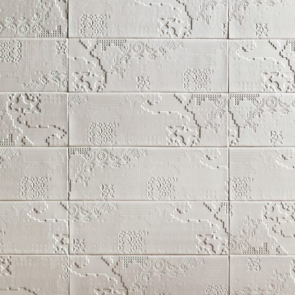 Eine weiß geflieste Wand mit einem Muster darauf, ausgestellt auf einer Badausstellung. | casaceramica
