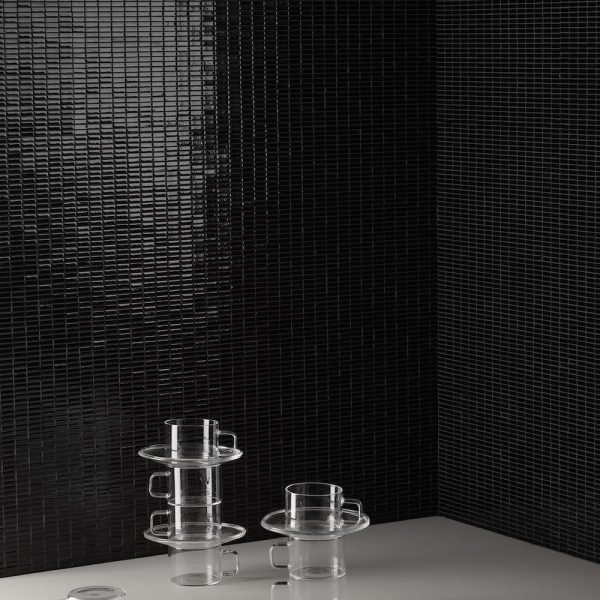 Ein schwarz gefliester Raum mit einer Glasvase und einer Vase. | casaceramica