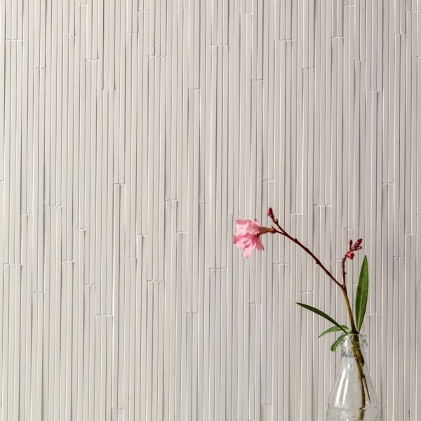 Eine rosa Blume in einer Vase vor einer weißen Wand. | casaceramica