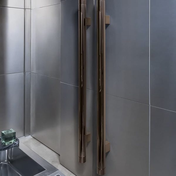 Ein Badezimmer mit einem Waschbecken aus Edelstahl und einem Handtuchhalter aus Holz für ein modernes Badausstellungsgefühl. | casaceramica