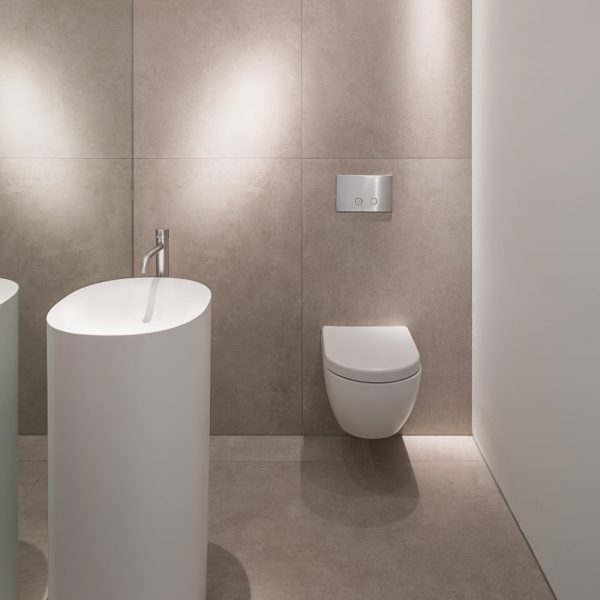 Ein modernes Badezimmer mit weißem Waschbecken und Toilette sowie sauberen Fliesen. | casaceramica